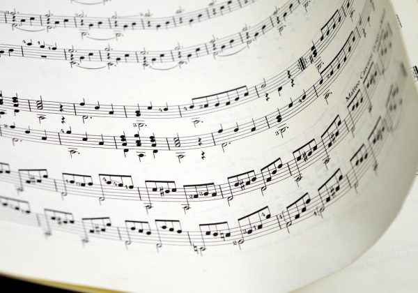 编辑在暗色屏幕前逐条核对音频转换参数，频谱曲线与码率数值同时显示，桌面散落着标注用的便签